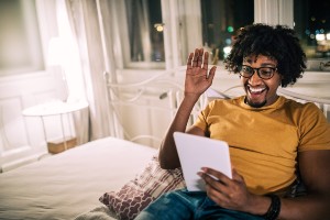 man waving at friend on ipad